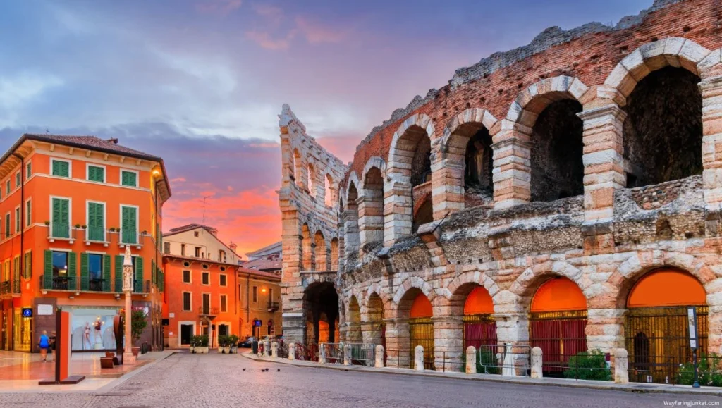The ancient Roman amphitheater in Verona with its massive stone arches and tourists walking nearby.